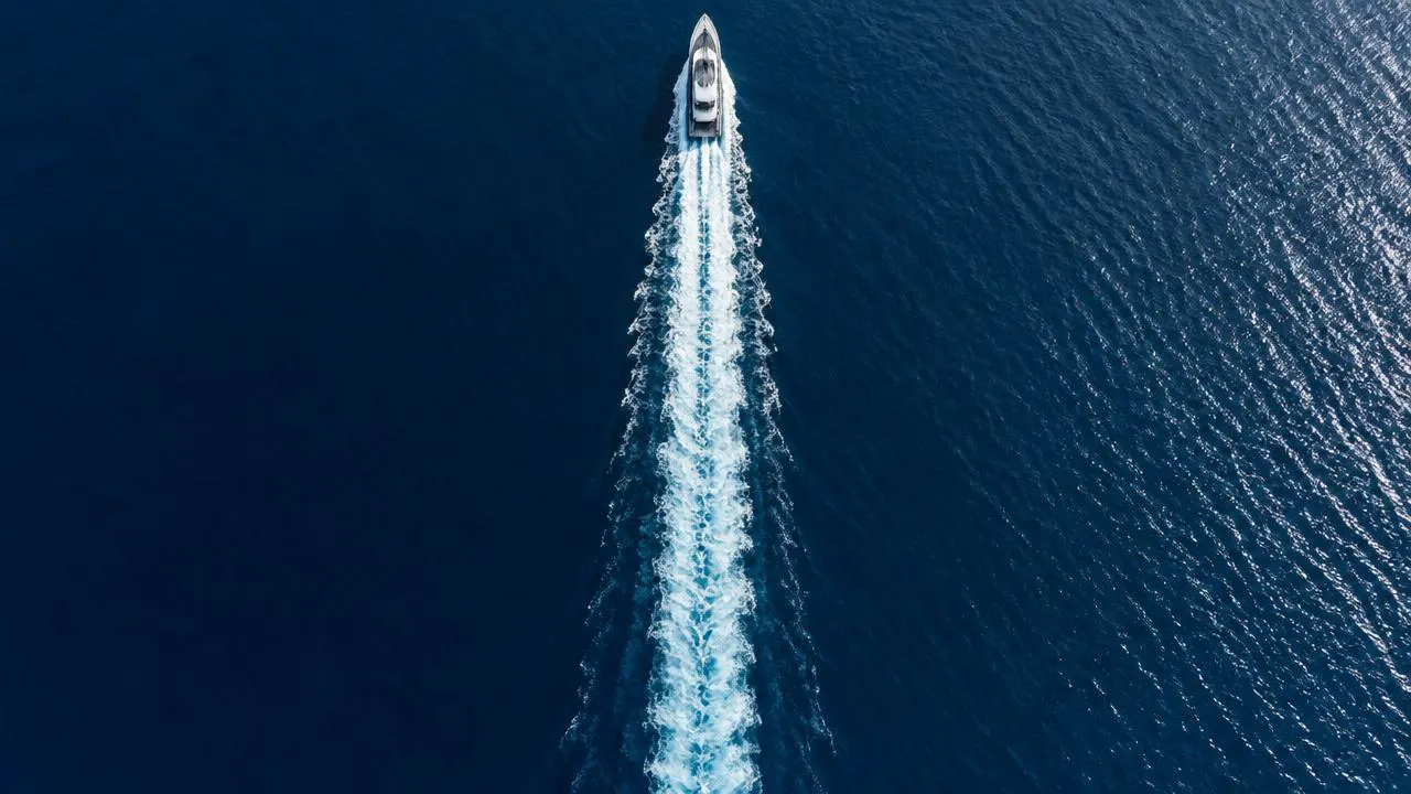 Overhead view of a yacht and its wake on deep blue sea
